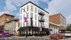 render showing hotel entrance with street-level restaurant, café terrace, and surrounding urban context